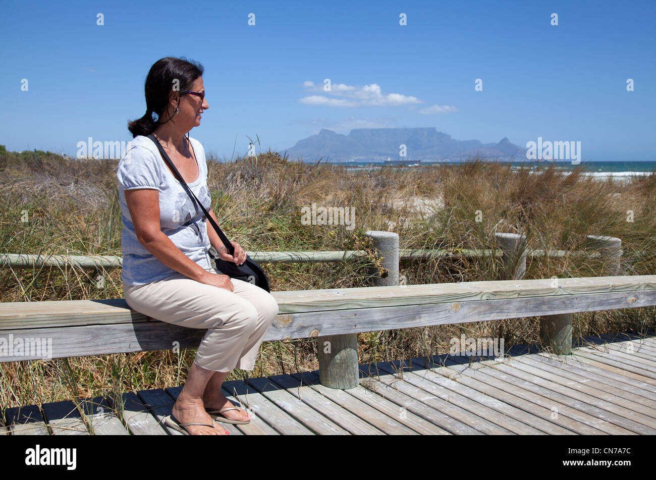Woman sitting at edge of Boardwalk in Big Bay - Cape Town Stock Photo