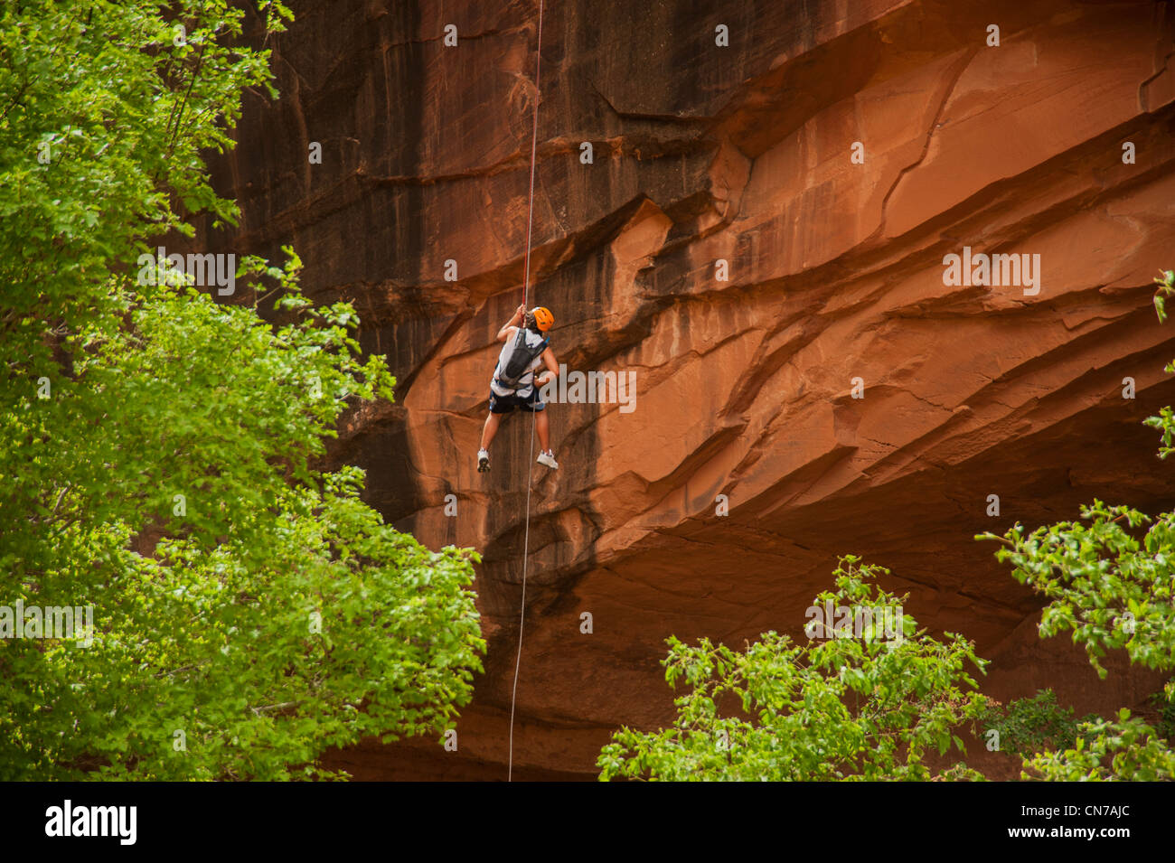 Rock climber rappelling down orange cliff in Utah Stock Photo Alamy