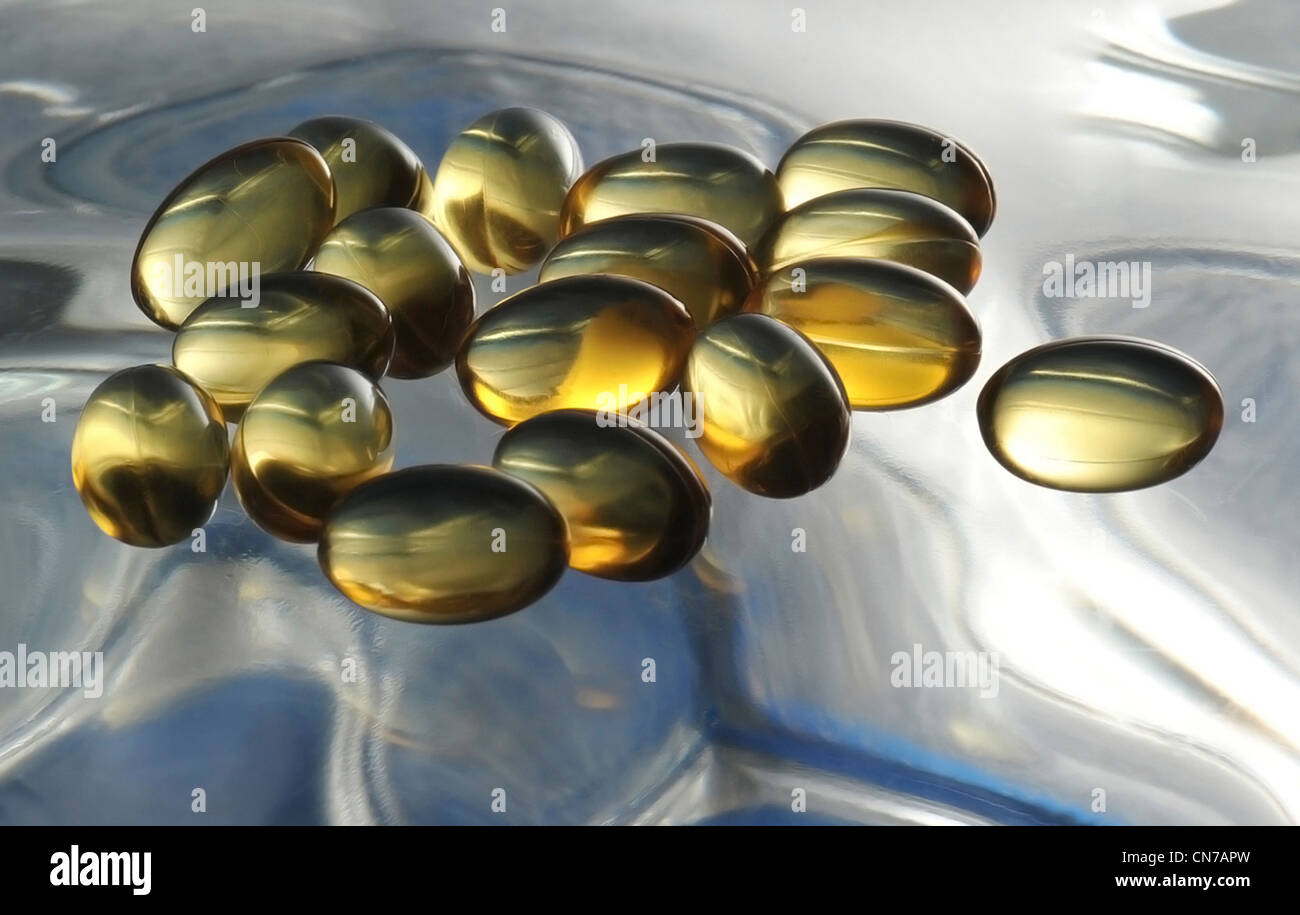 loose vitamin E capsules backlighted on glass Stock Photo