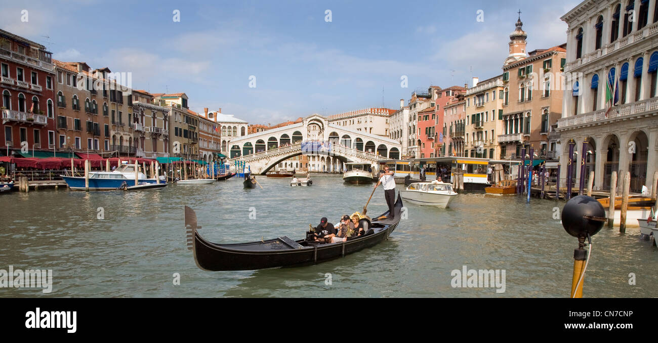 Venetian gondola rowing boat with tourists on the Grand Canal, Venice. Rialto bridge in background Stock Photo