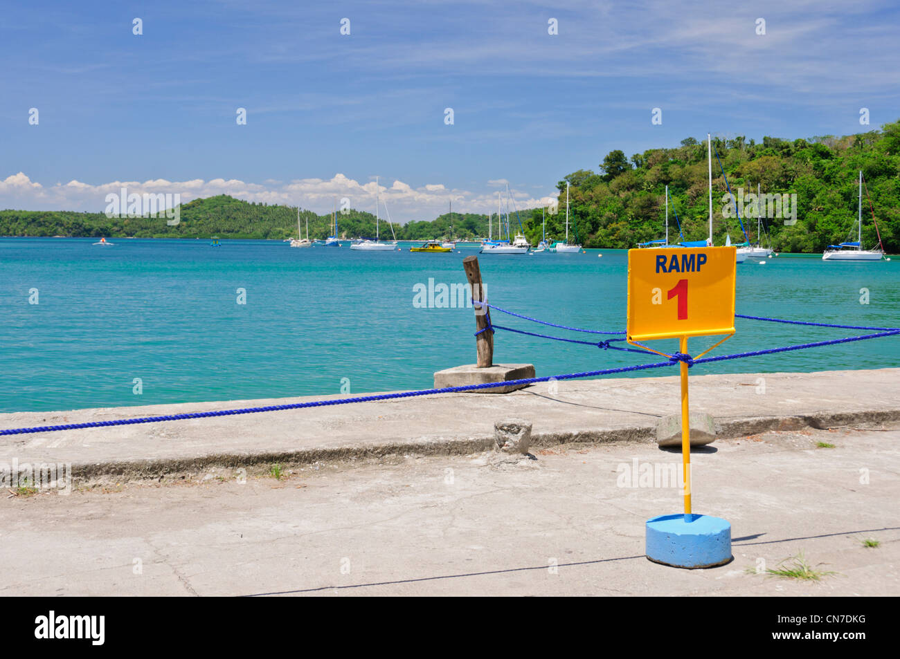 Muelle Pier, Puerto Galera Bay, Oriental Mindoro, Philippines, Southeast Asia, blue ocean water sky, sailing yachts, sign Ramp 1 Stock Photo