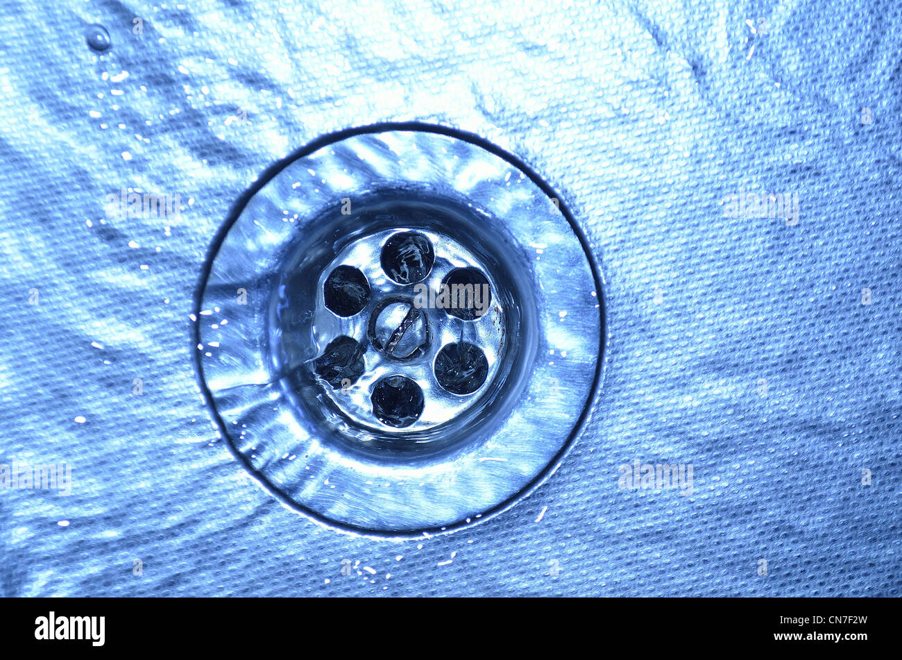 flowing water on metallic sink and drain hole closeup; focus on drain holes Stock Photo Alamy