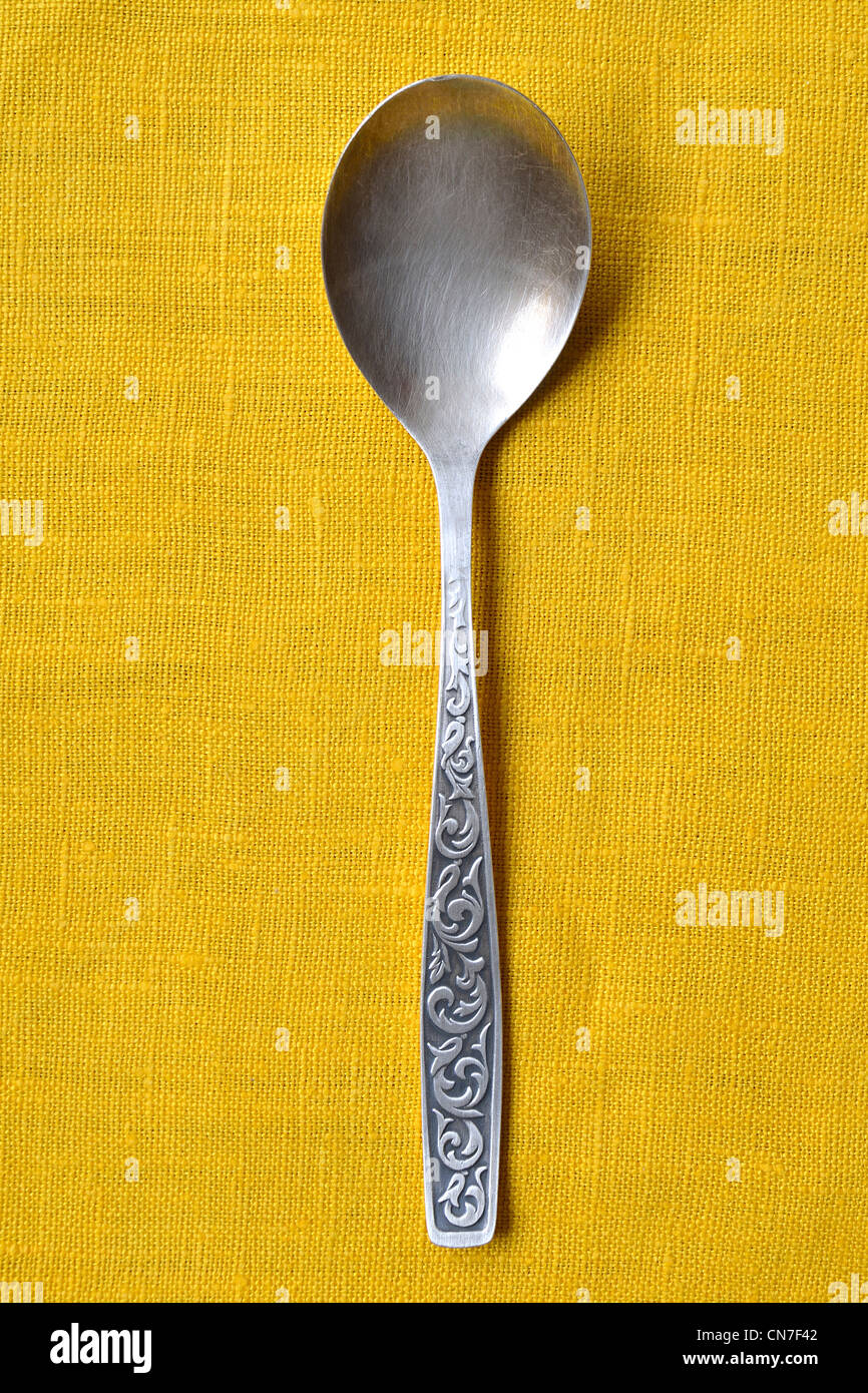vintage silver spoon on the yellow tablecloth background Stock Photo