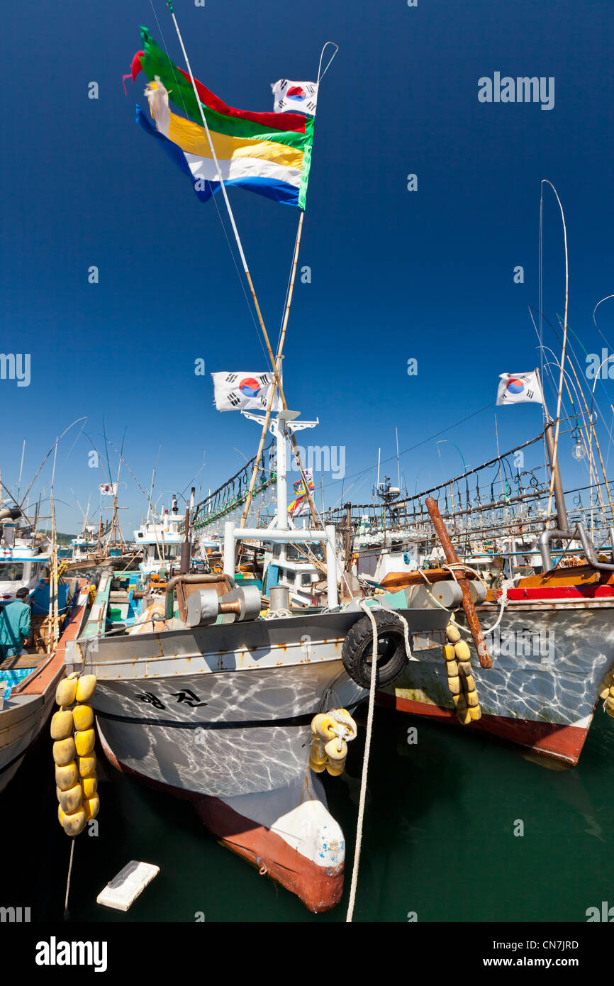 South Korea, Jeju Province, Seongsan, Korean flag (Taegukgi) and fishing boats in the port of Seongsan Stock Photo