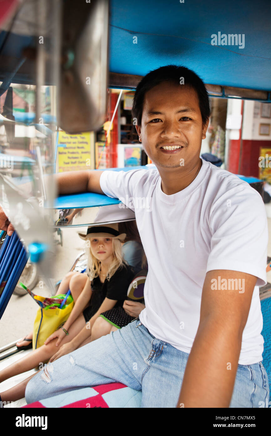 Smiling pedicab driver with passengers Stock Photo