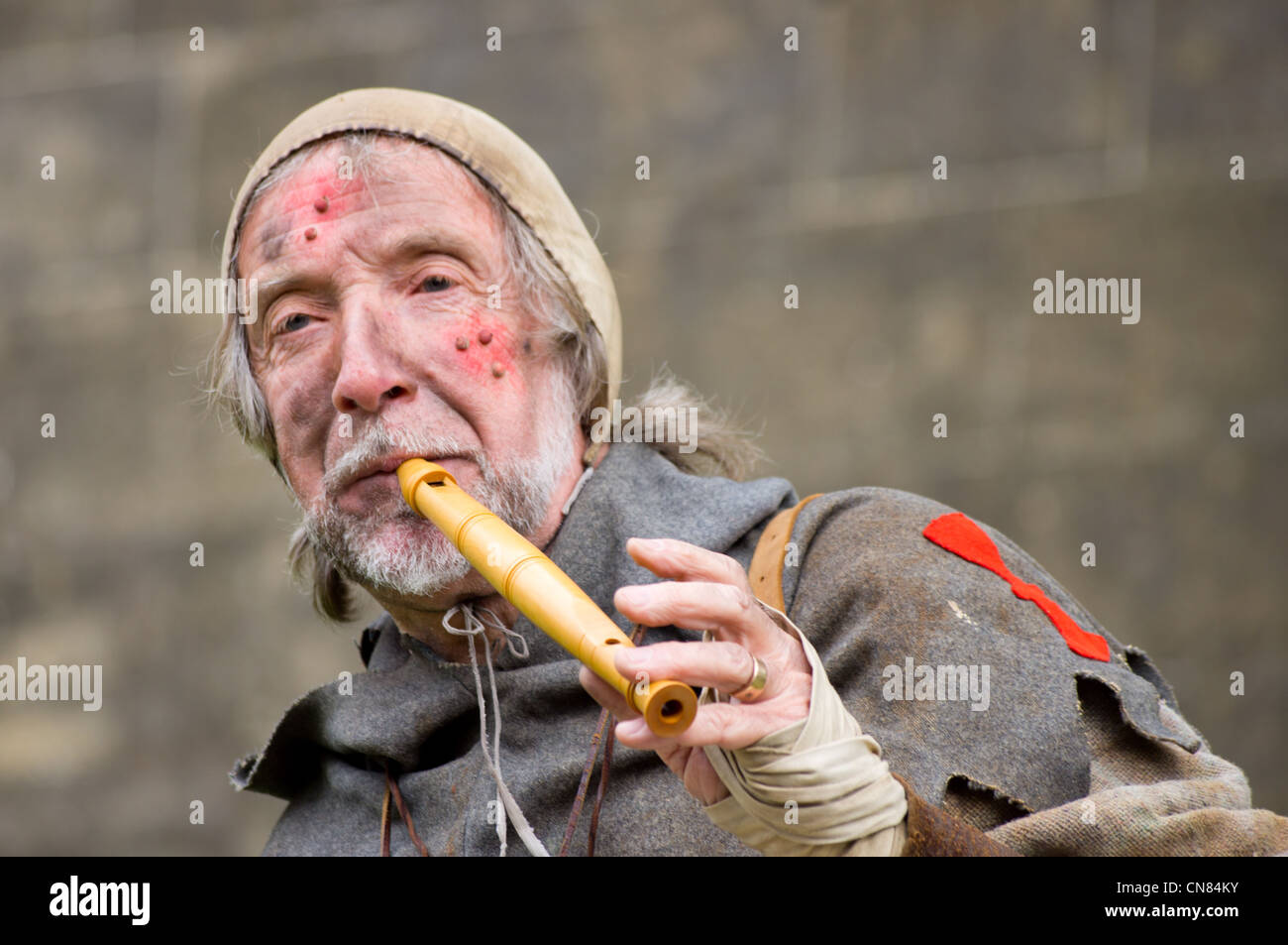 A medieval story teller plays a tune on his flute to call an audience. "History in action" re-enactment at Arundel Castle Stock Photo