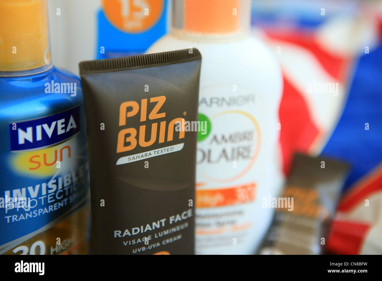 Suntan lotions beside a red and white stripped bikini at the beach