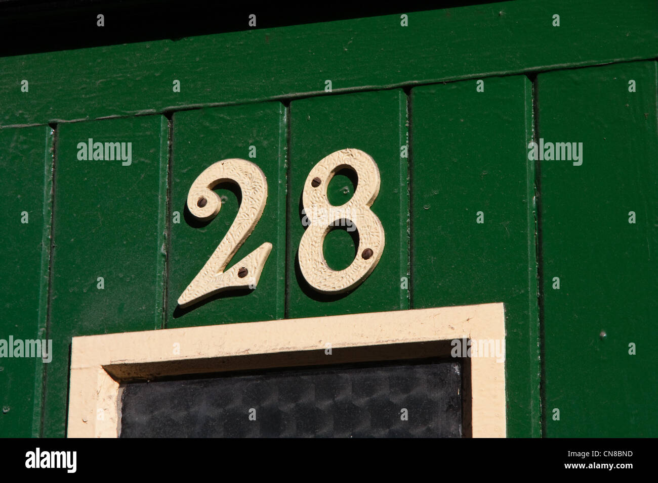 Cream number 28 on green door Stock Photo