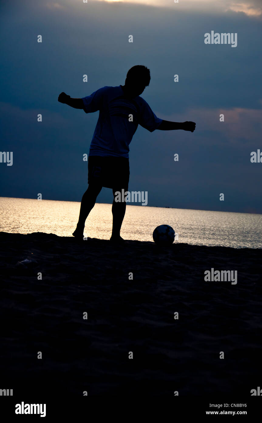 silhouette of man playing soccer on the beach Stock Photo