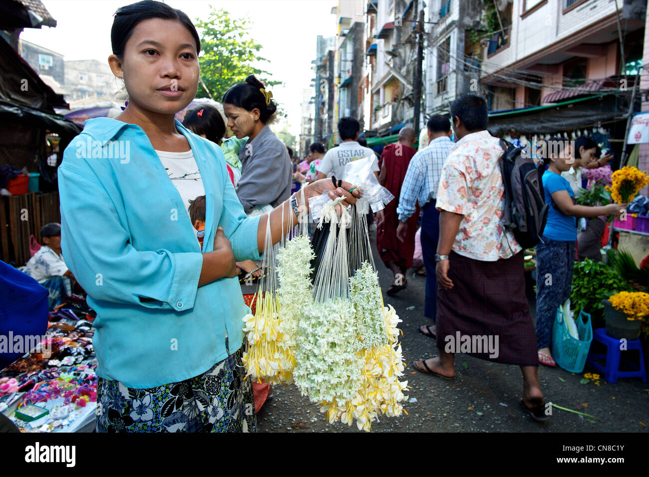 A young Burmese girl sells jasmine flower garlands in a street market