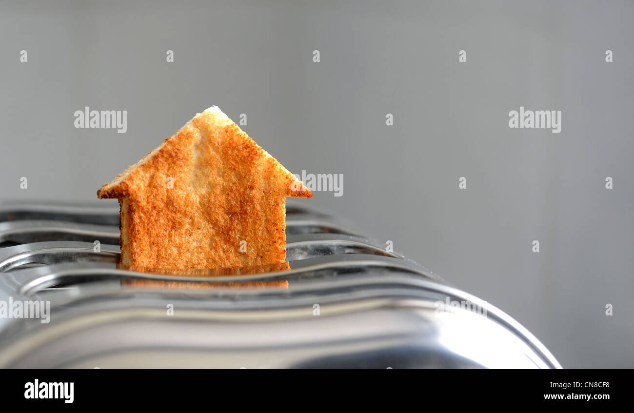 PIECE OF TOAST IN SHAPE OF HOUSE IN A TOASTER RE HOUSING MARKET PROPERTY HOME BUYING BUYERS FIRST TIME HOMES COSTS ETC UK Stock Photo