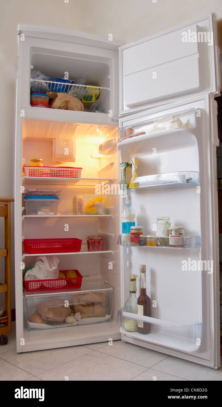 An open white refrigerator with stuff within Stock Photo