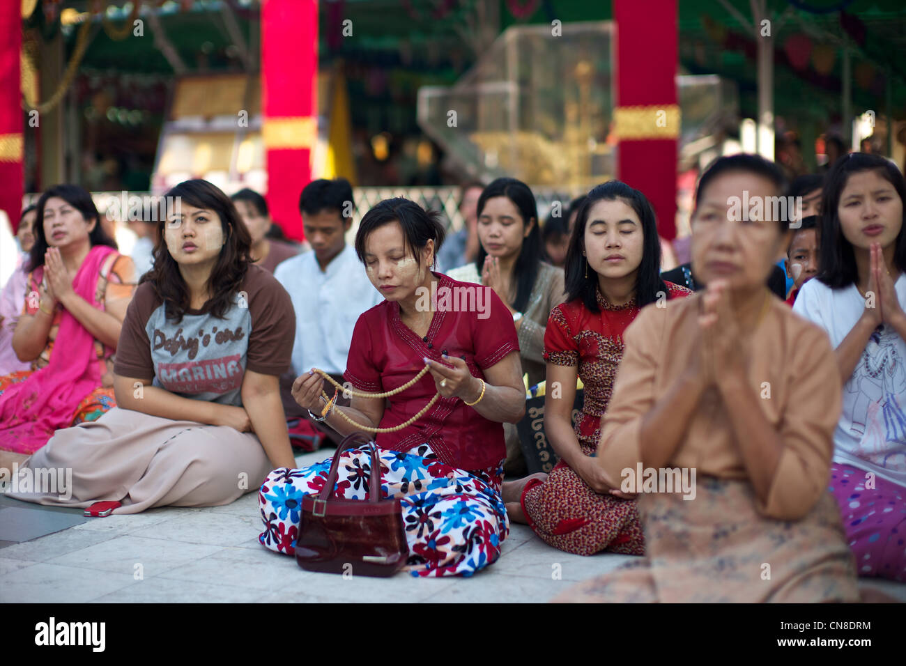 Burmese women pray in at the sacred Buddhist site of Shwedagon Paya, Yangon (Rangoon), Myanmar (Burma) Stock Photo