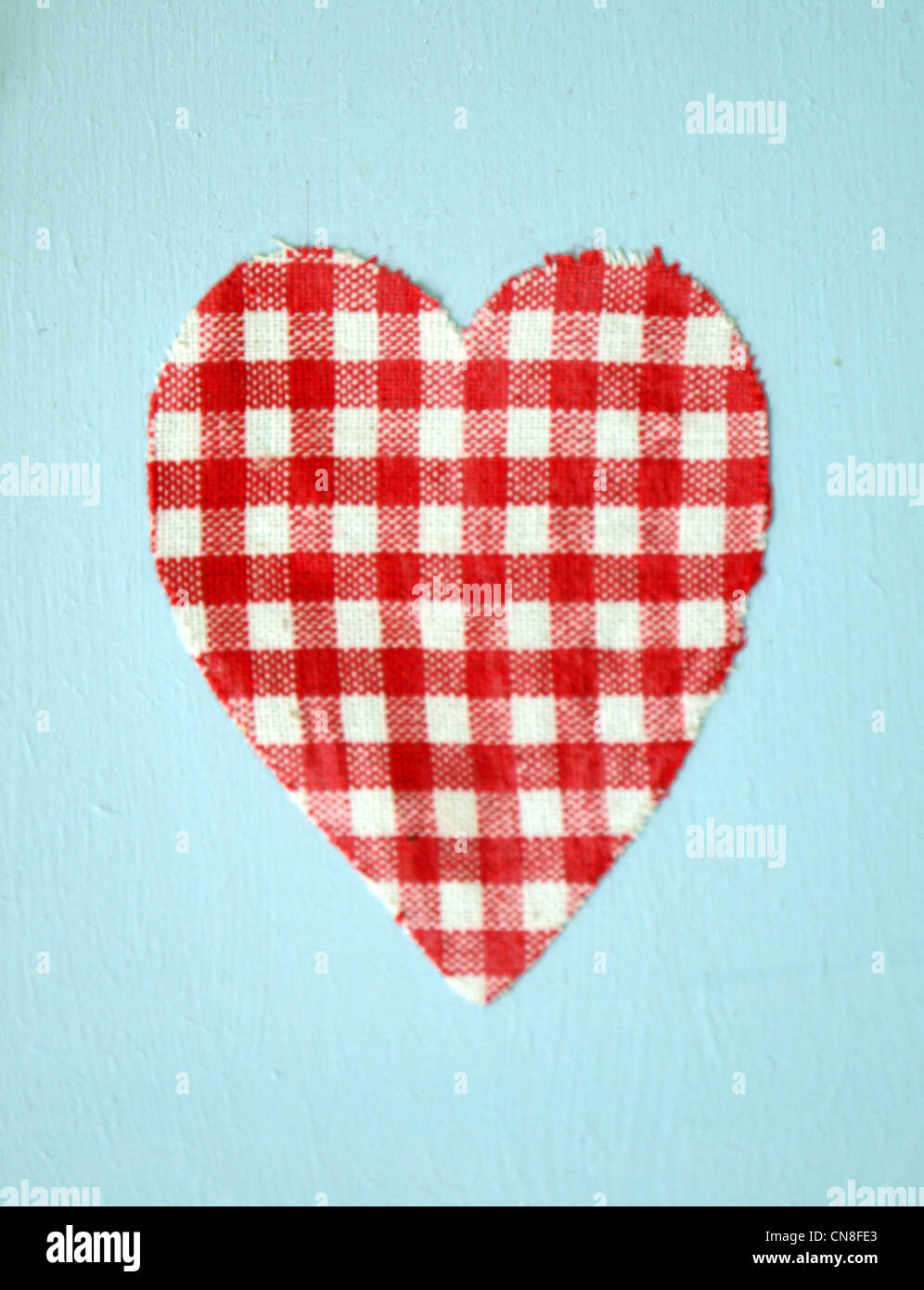 A red and white check heart on a light blue background Stock Photo