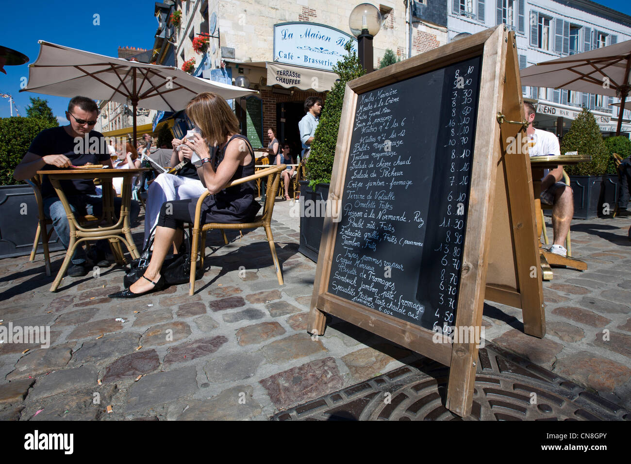 France, Calvados, Honfleur, La Maison Bleue restaurant and customers sitting on the terrace with menu in the foreground Stock Photo