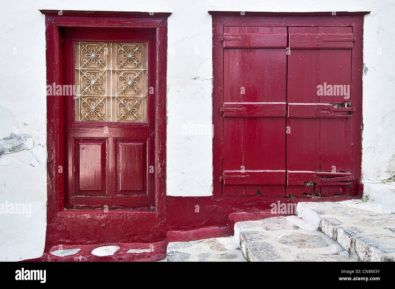 Old house in Hydra island, Greece with doors and shutter blinds painted in red Stock Photo