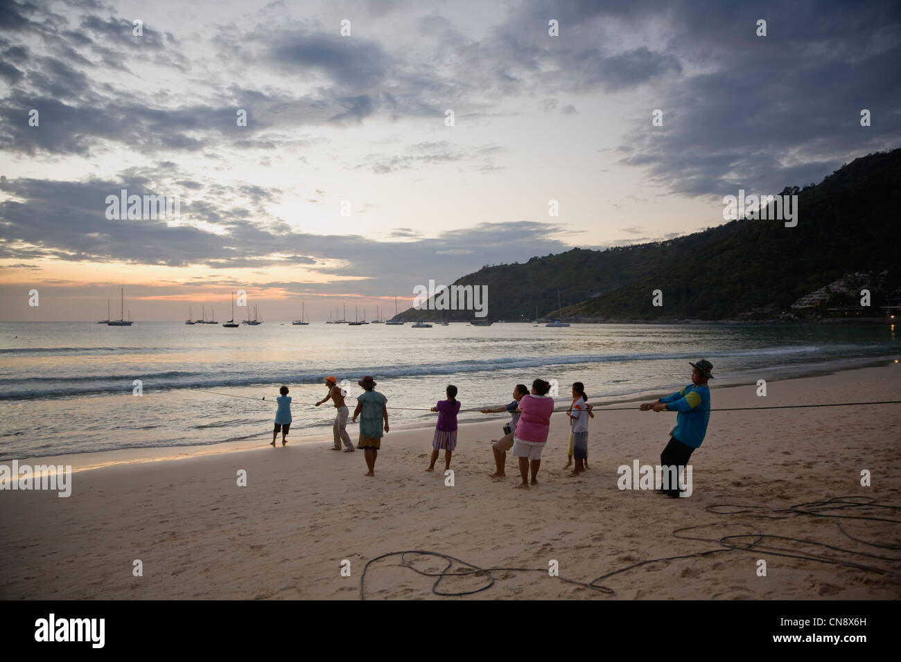 Locals pulling in a fishing net at Nai Harn Beach, Phuket, Thailand Stock Photo