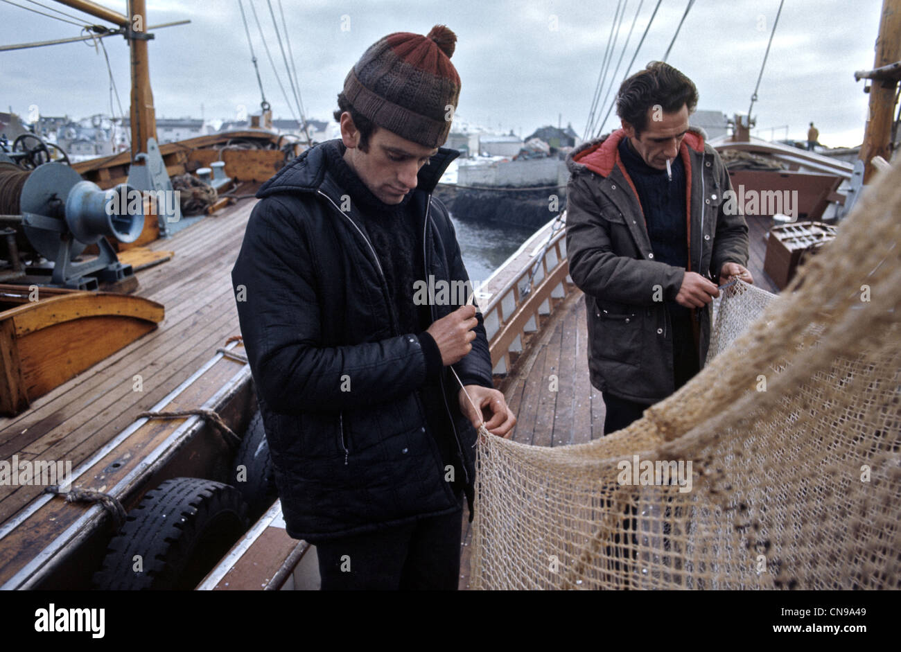 fishermen mending nets on deck of small boat in Scalpay Outer Hebrides Stock Photo