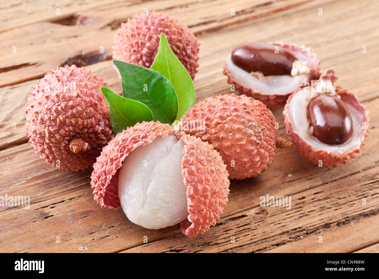 Lychee with leaves on a wooden table. Stock Photo