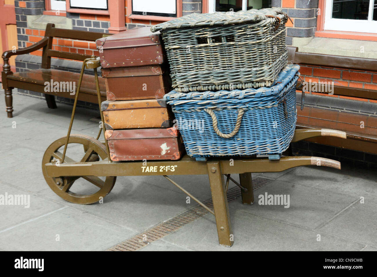 Old period traditional station wheelbarrow with left luggage of suitcases, hamper  and basket. Stock Photo
