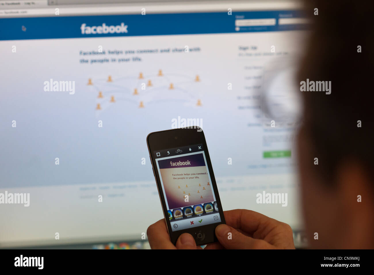 A woman holds her iPod touch and photographs the Facebook web page using an Instagram app Stock Photo