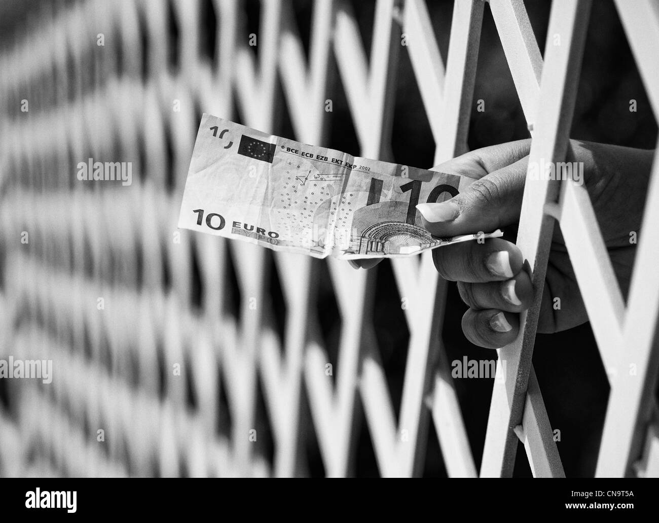Hand hold money trough bars - BW Stock Photo