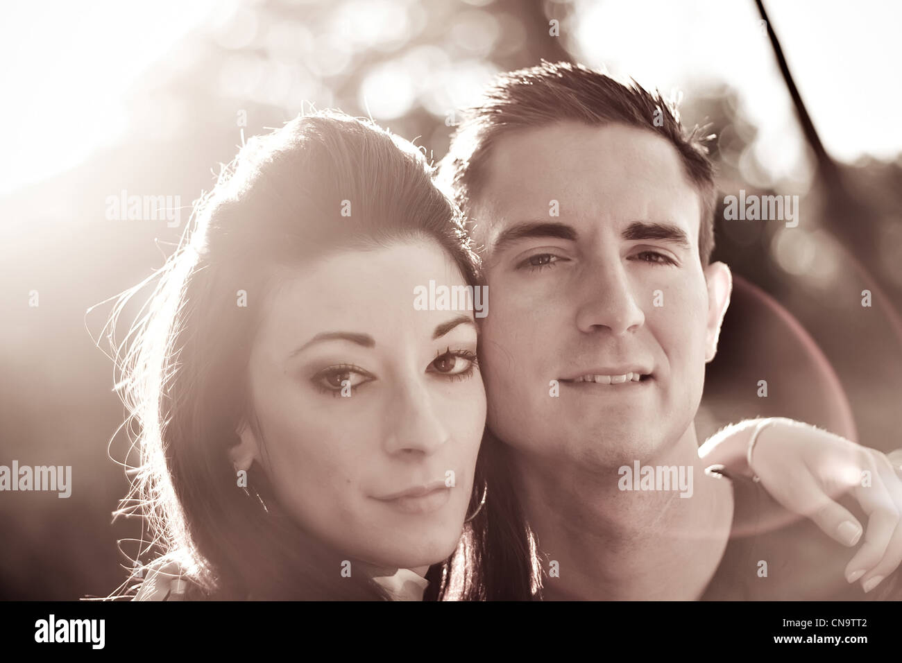 A good looking young couple posing together. Backlit lighting with strong lens flare and sepia tone. Stock Photo
