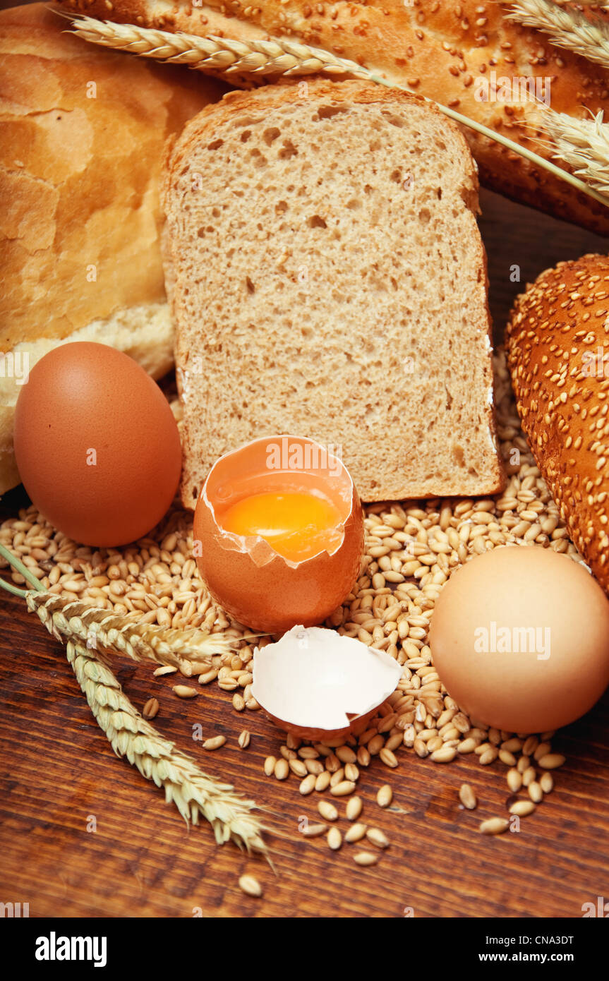 Wheat bread and grains and wheat ears with eggs on a wooden table Stock