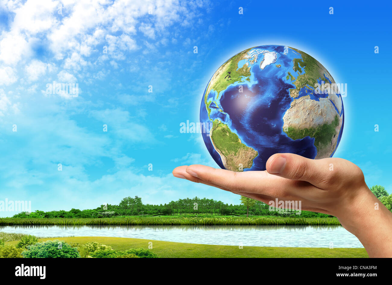 Man hand with earth globe on it and a beautiful green landscape with ...