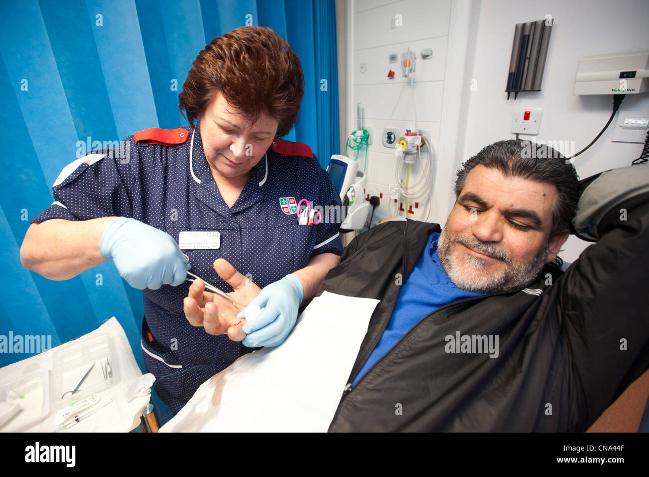 A nurse stitches a mans hand in A&E Stock Photo
