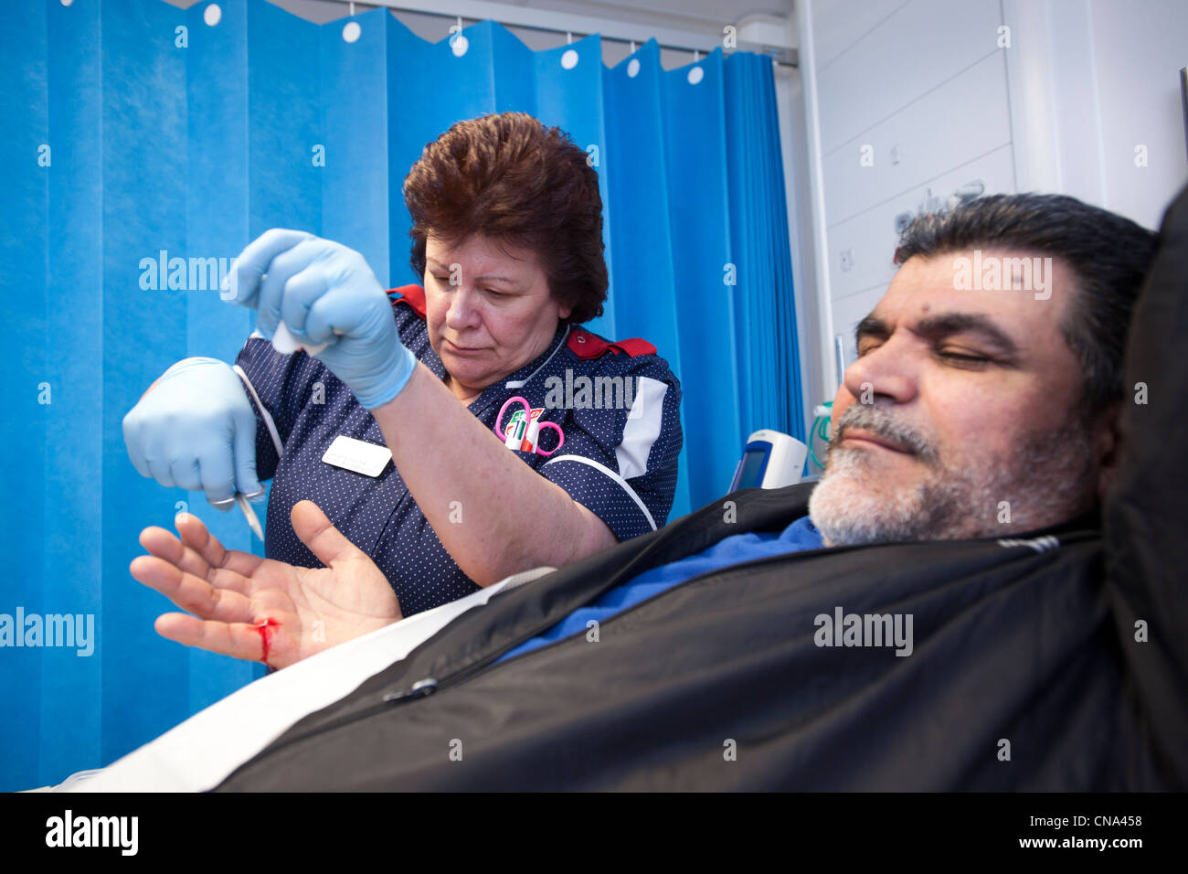 A nurse stitches a mans hand in A&E Stock Photo