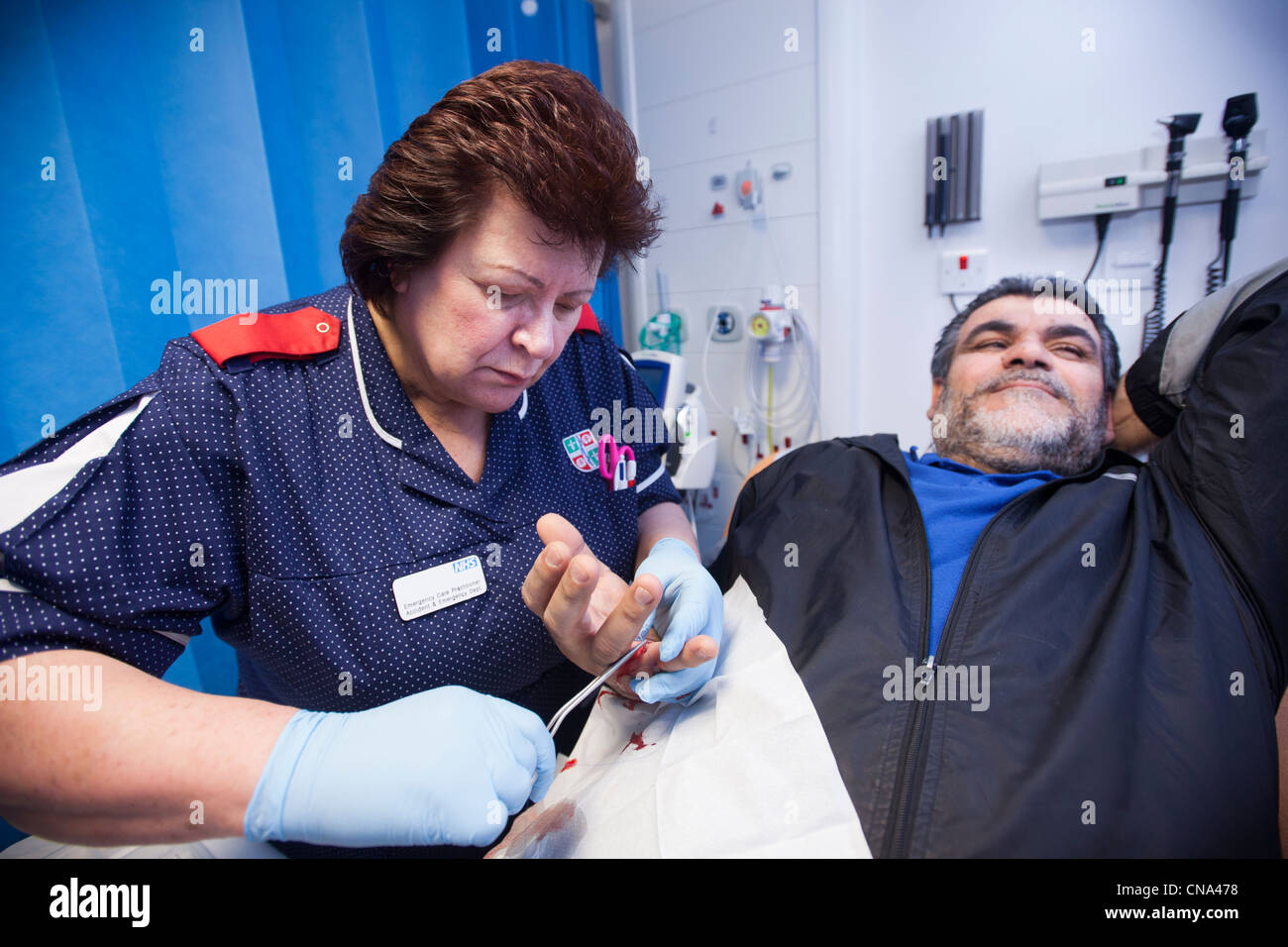 A nurse stitches a mans hand in A&E Stock Photo