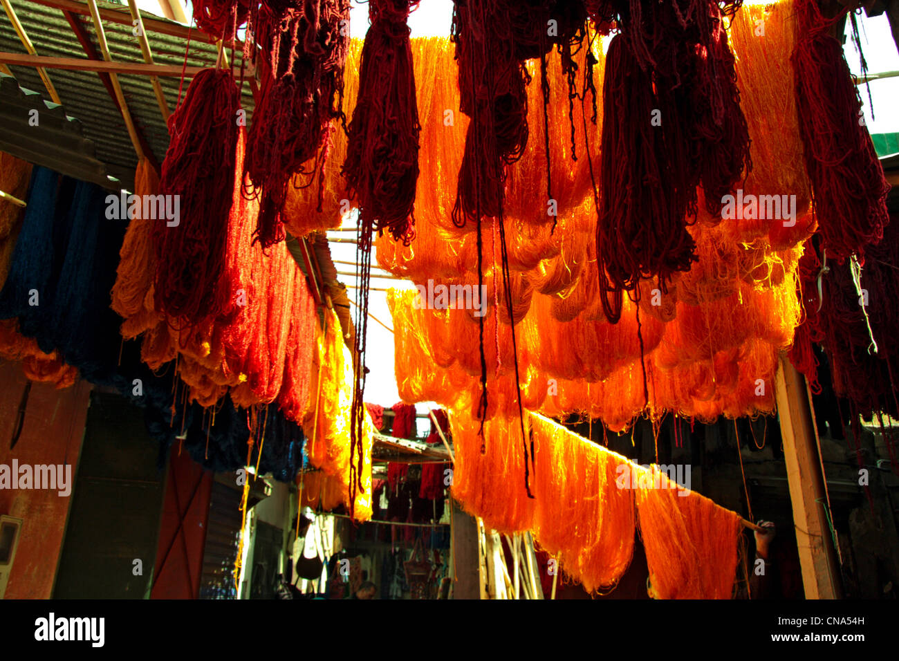 Sheaves of freshly dyed red and yellow wool hang drying in the Dyers souk/Souq des Sebbaghine in the medina, Marrakech, Morocco Stock Photo