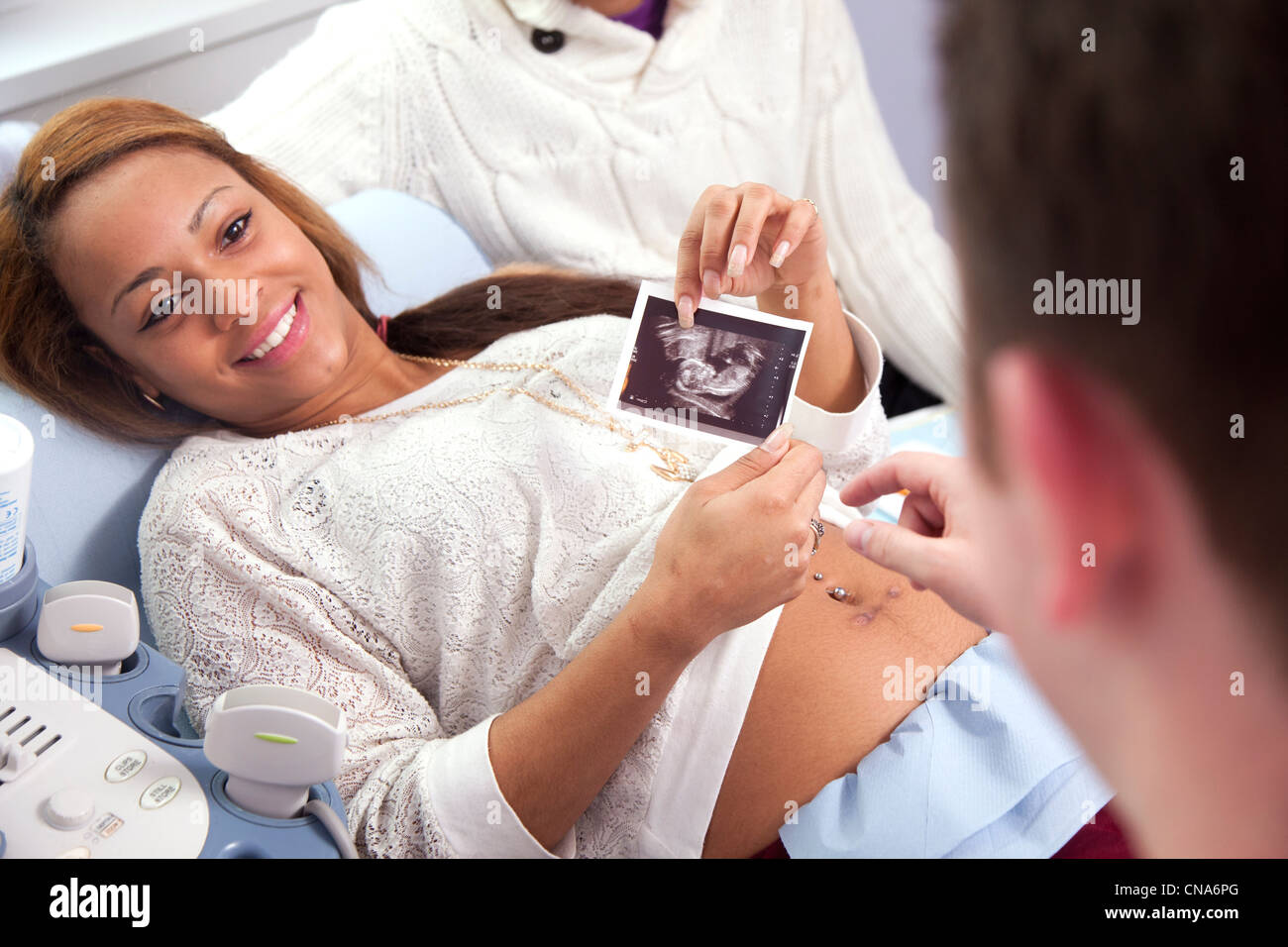 A young pregnant woman holds a picture of her unborn baby during an ultrasound scan UK Stock Photo
