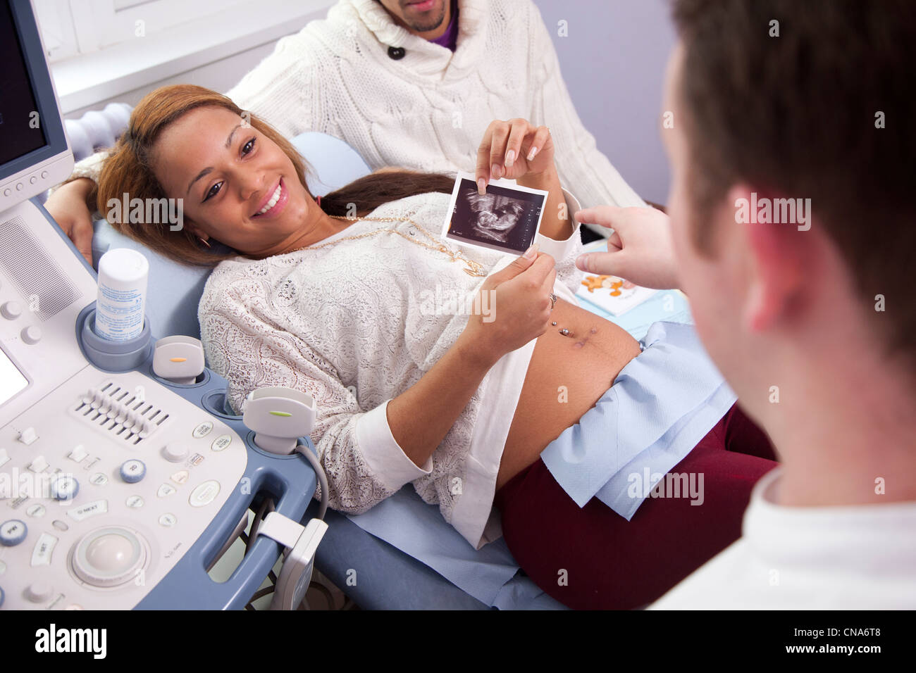 A young pregnant woman holds a picture of her unborn baby during an ultrasound scan UK Stock Photo