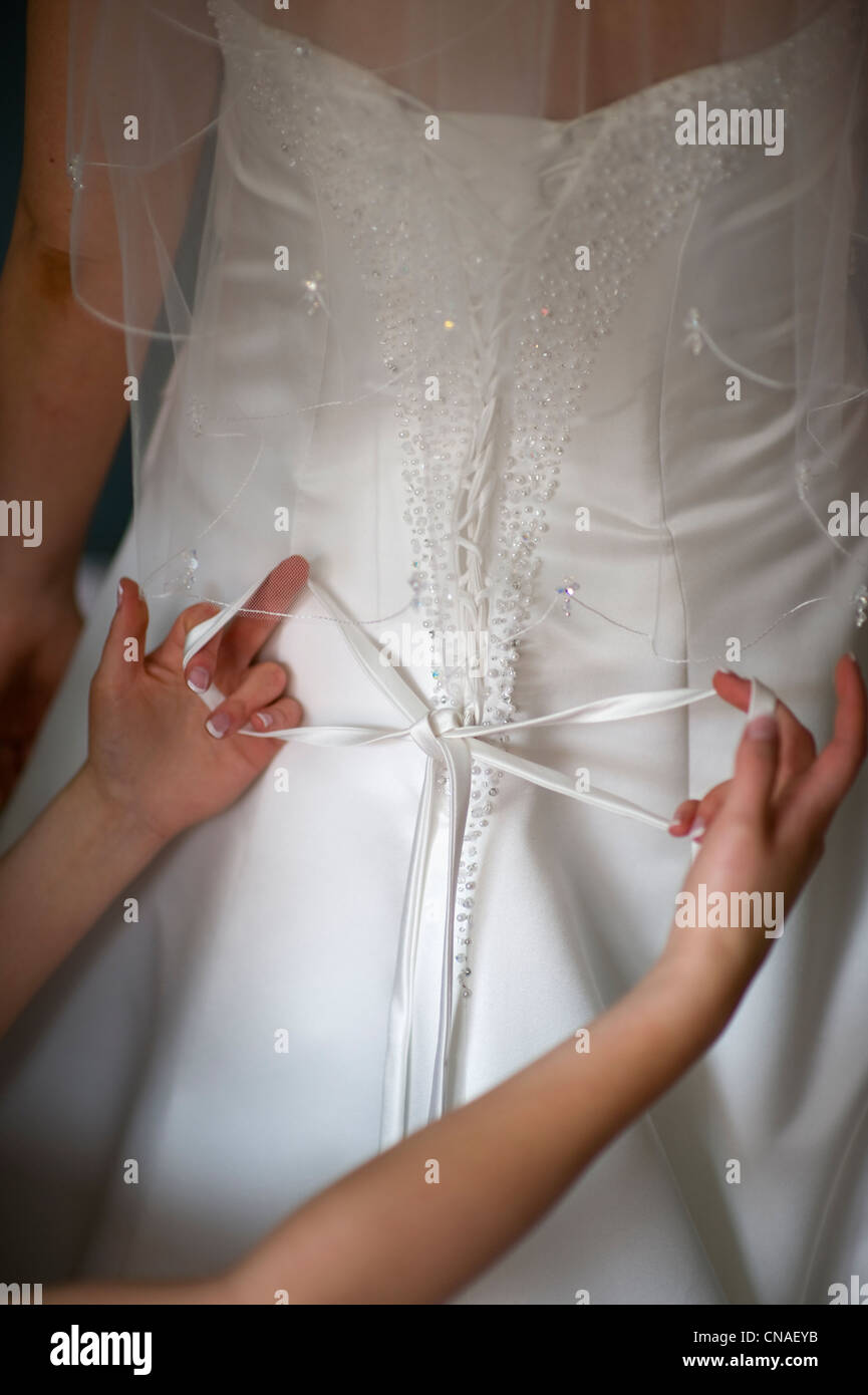 tying the bow on the back of a wedding dress worn by a bride Stock