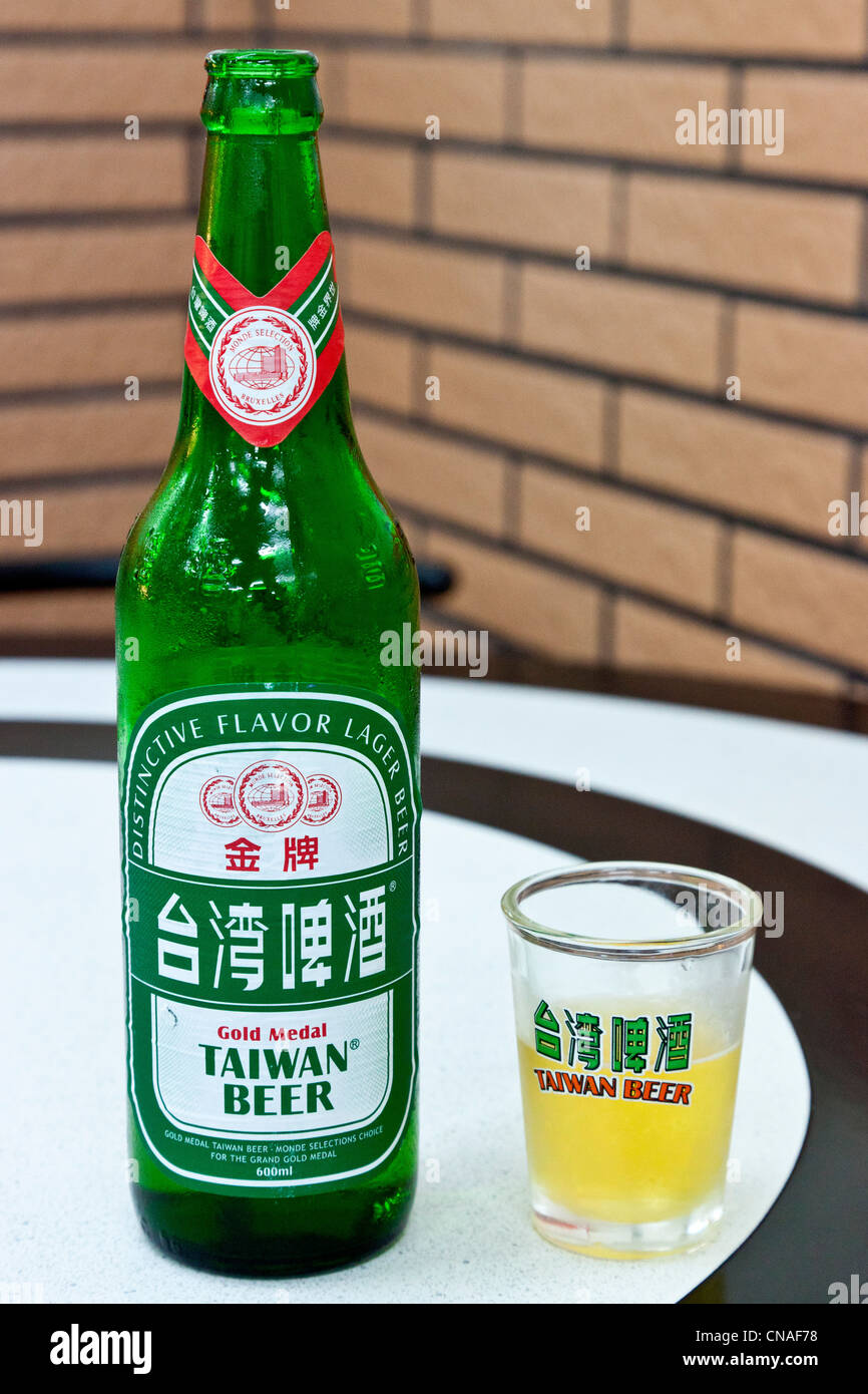 Open bottle of Taiwan Beer gold medal lager with branded glass on table. JMH5889 Stock Photo