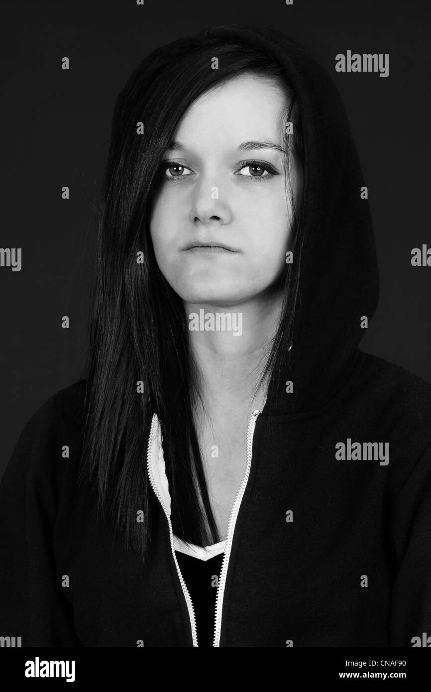 Black and white portrait of a young woman, teen or student looking sad or depressed, studio shot with black background. Stock Photo