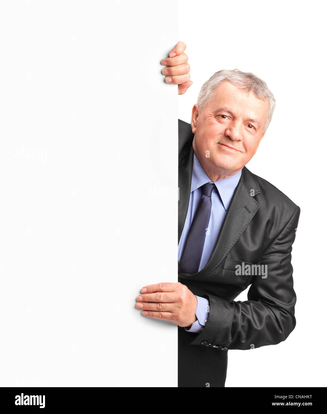 Smiling mature businessman holding a white panel and gesturing isolated on white background Stock Photo