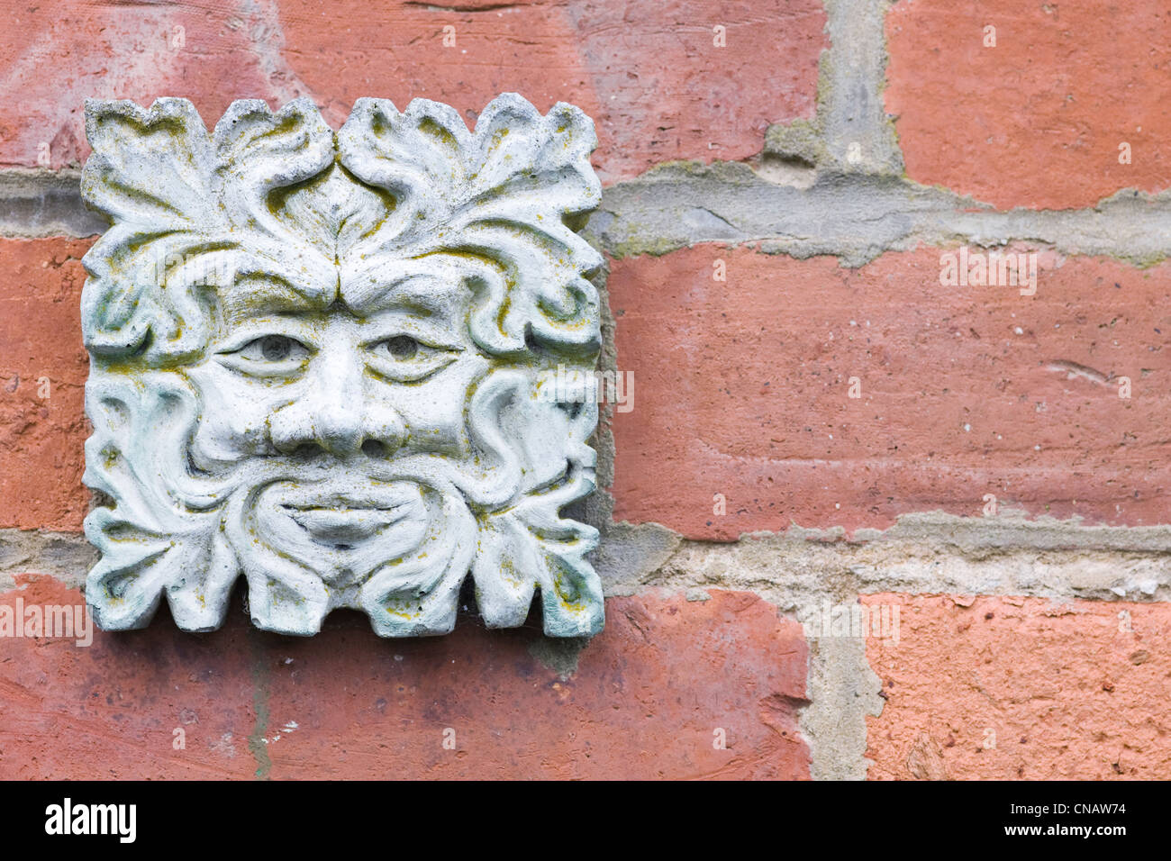 Green Man plaque on an old redbrick wall. Stock Photo