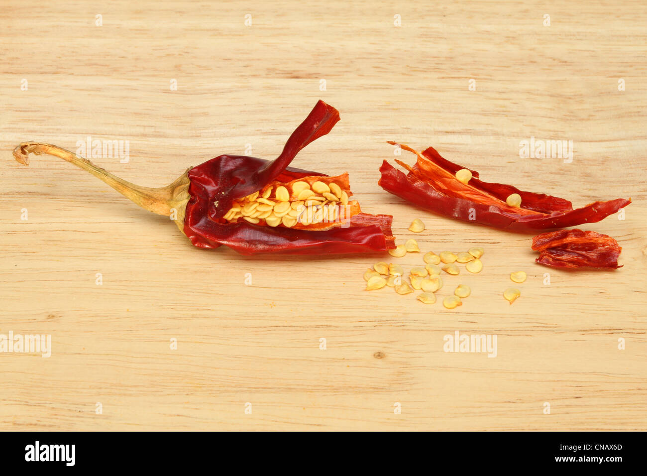 Dried red chilli pepper and seeds on a wooden board Stock Photo