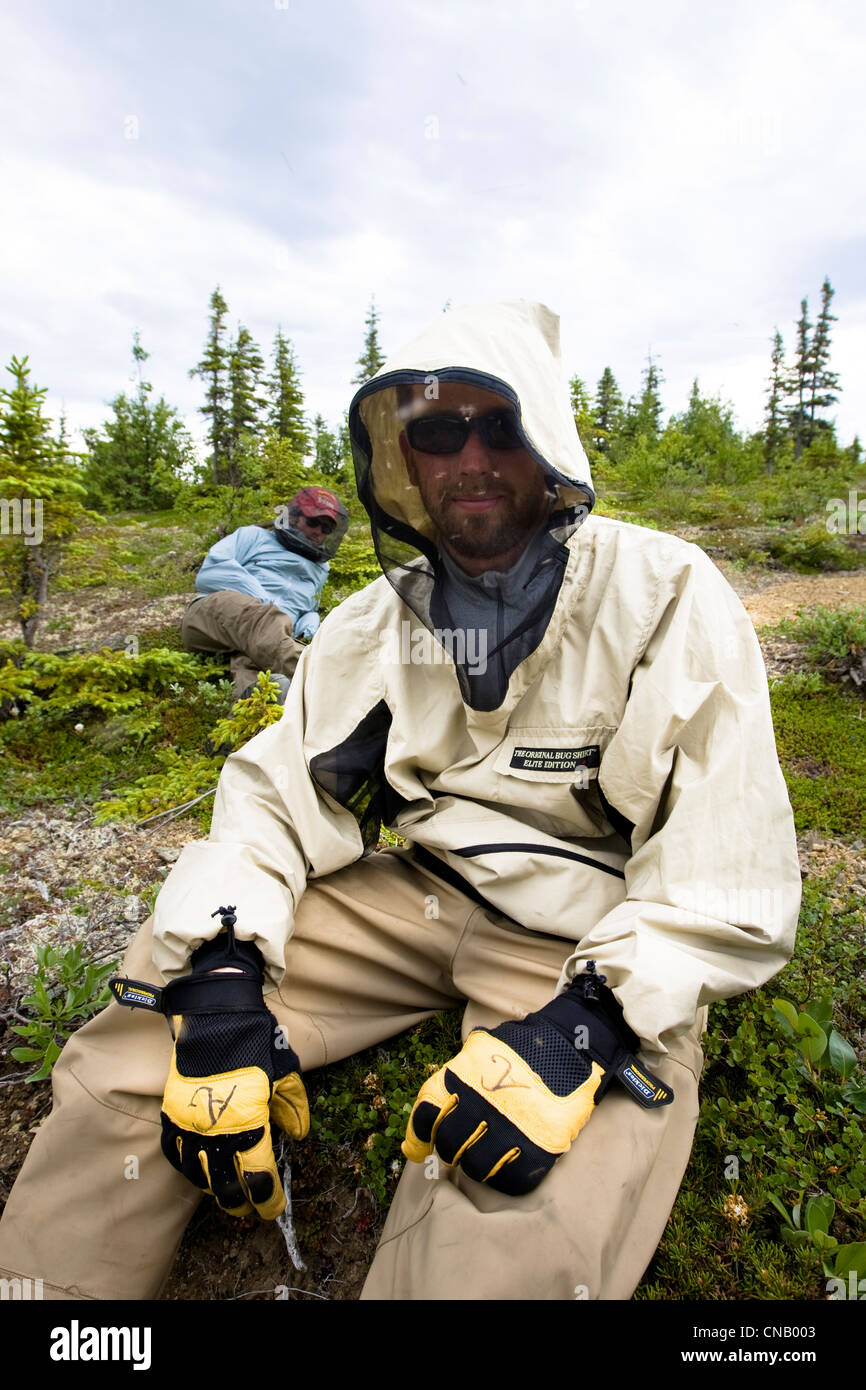 Two fishermen wear mosquito nets and bug shirts while taking a break along the Koktuli River, Bristol Bay area, Alaska Stock Photo