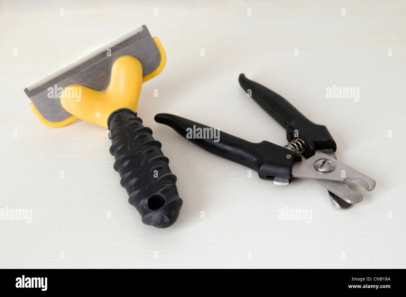 Selection of dog grooming tools including nail clippers, and shedding comb taken against a plain