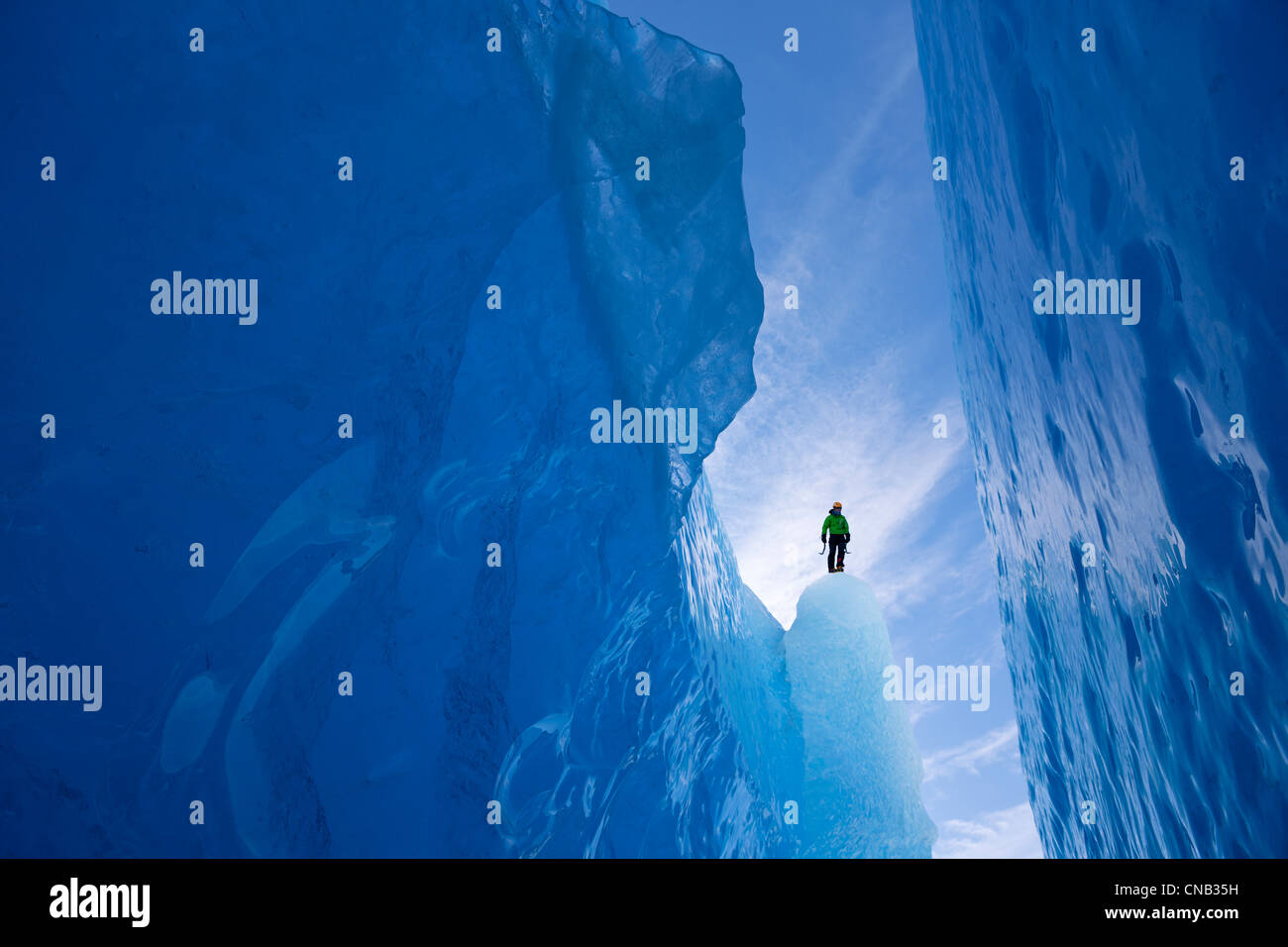 An ice climber surveys a wide crevasse from within Mendenhall Glacier, Juneau, Southeast Alaska, Winter Stock Photo
