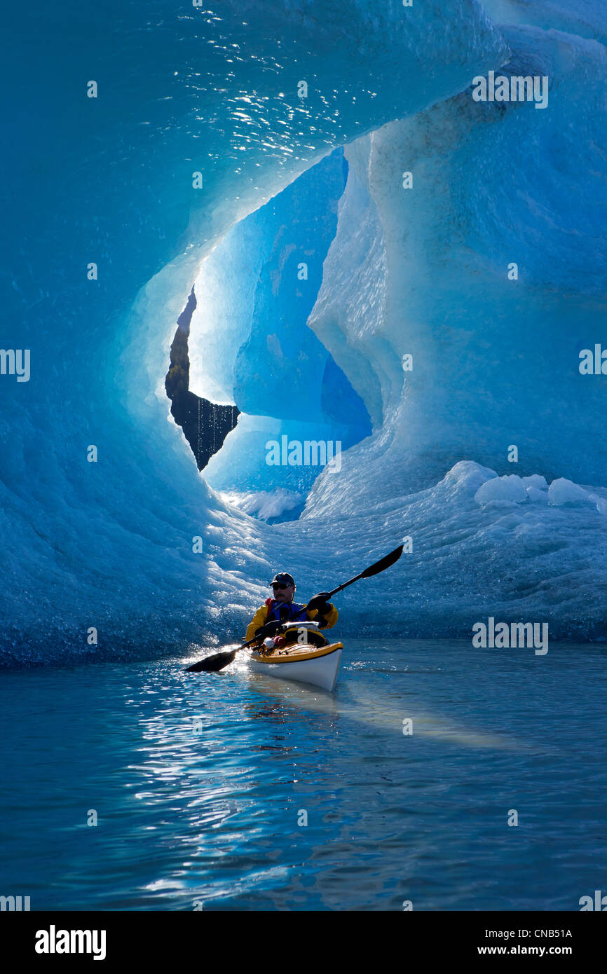 Sea kayaker on Mendenhall Lake with big blue iceberg in the background, Southeast Alaska, Summer Stock Photo