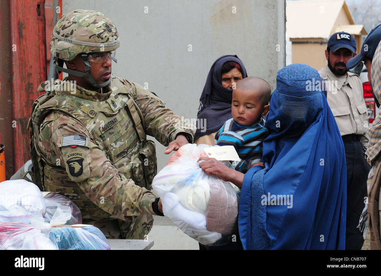 US Army soldier Herbert Duvernay hands out clothing to an Afghan woman wearing a full body burqa at El Salam Egyptian hospial Stock Photo