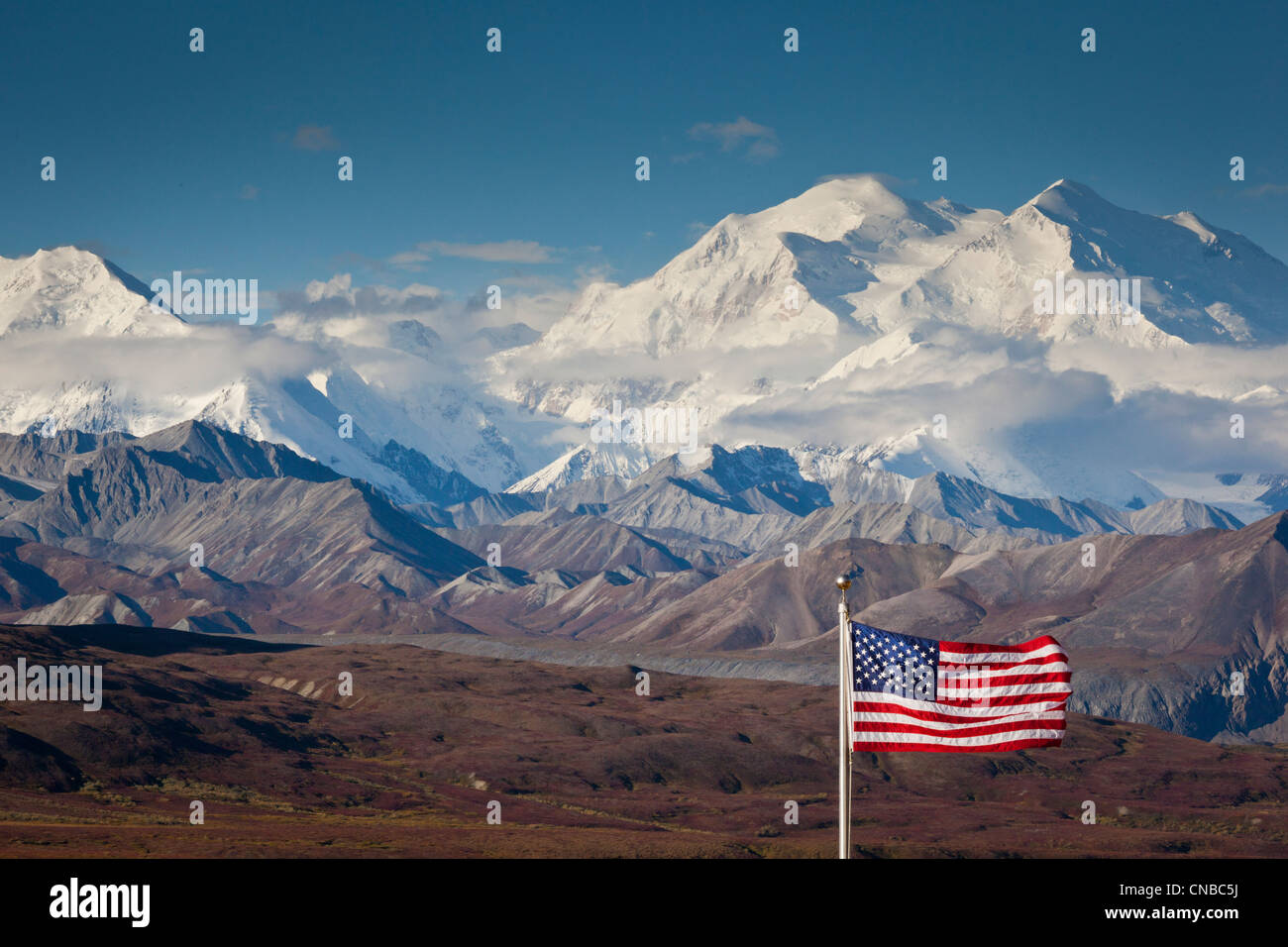 An American flag flys in the wind at Eielson Visitor Center with Mt. Mckinley in the background,  Denali National Park, Alaska Stock Photo