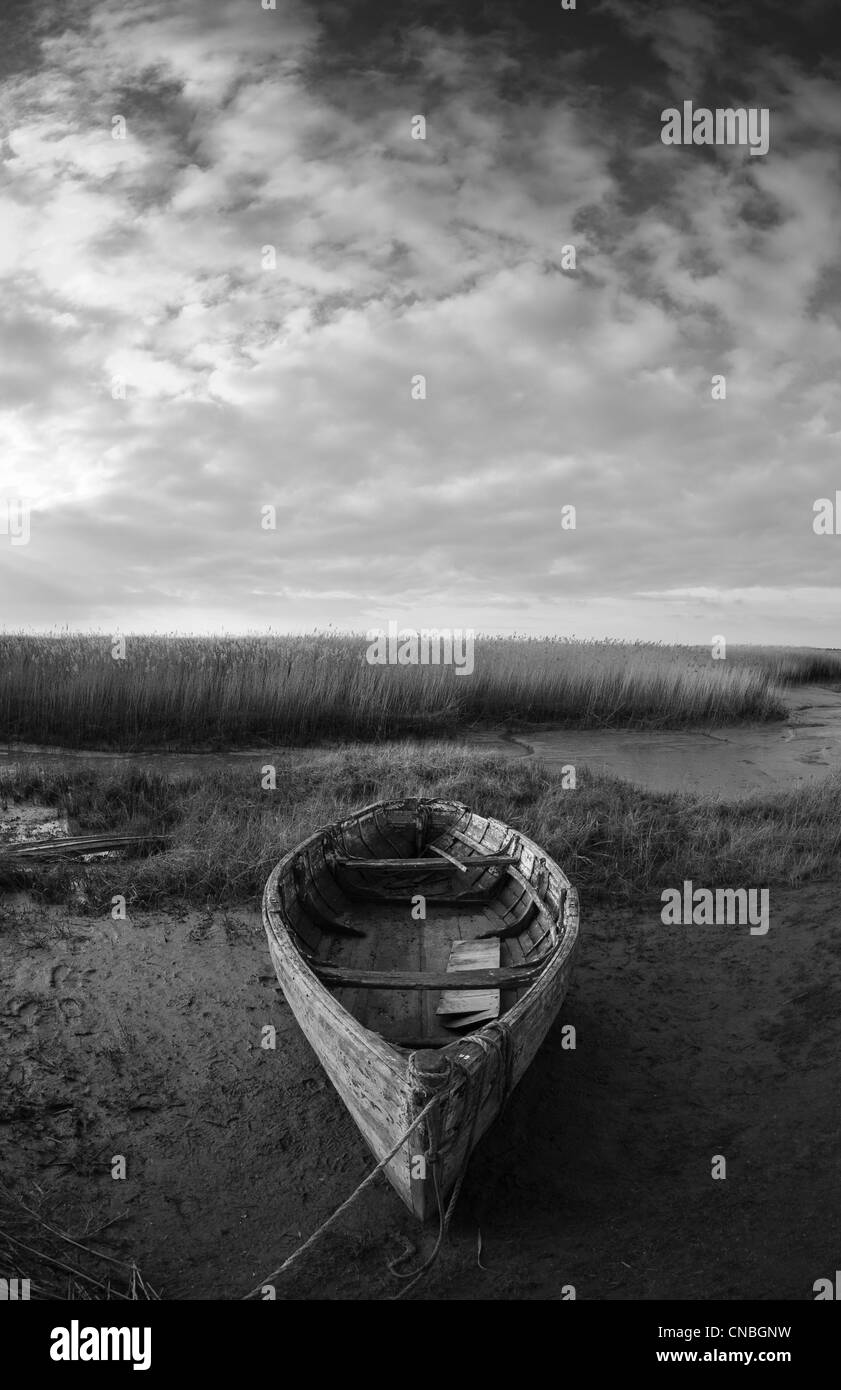 An old wooden boat on the edge of the marsh at Brancaster Staithe on the North Norfolk coast. Stock Photo