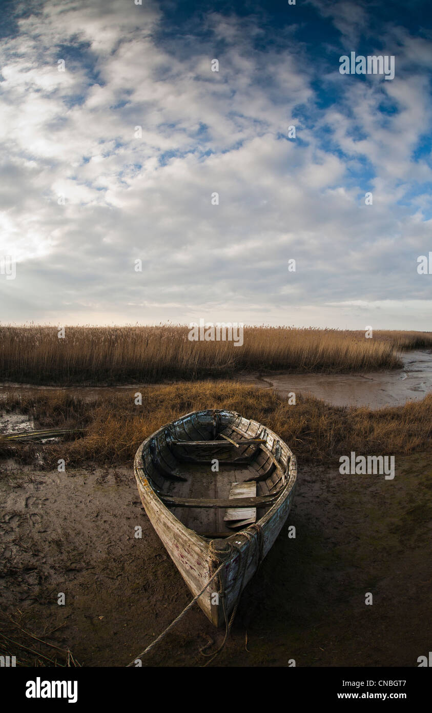 An old wooden boat on the edge of the marsh at Brancaster Staithe on the North Norfolk coast. Stock Photo