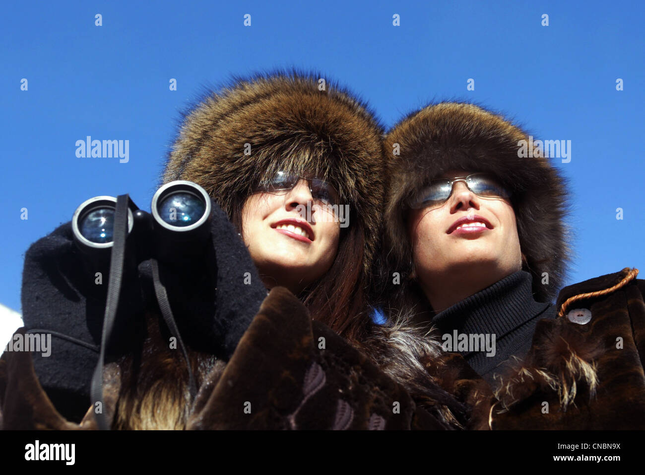 Two women with binoculars at the horse races, Sankt Moritz, Switzerland Stock Photo